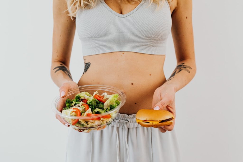 femme qui tient une salade et un burger